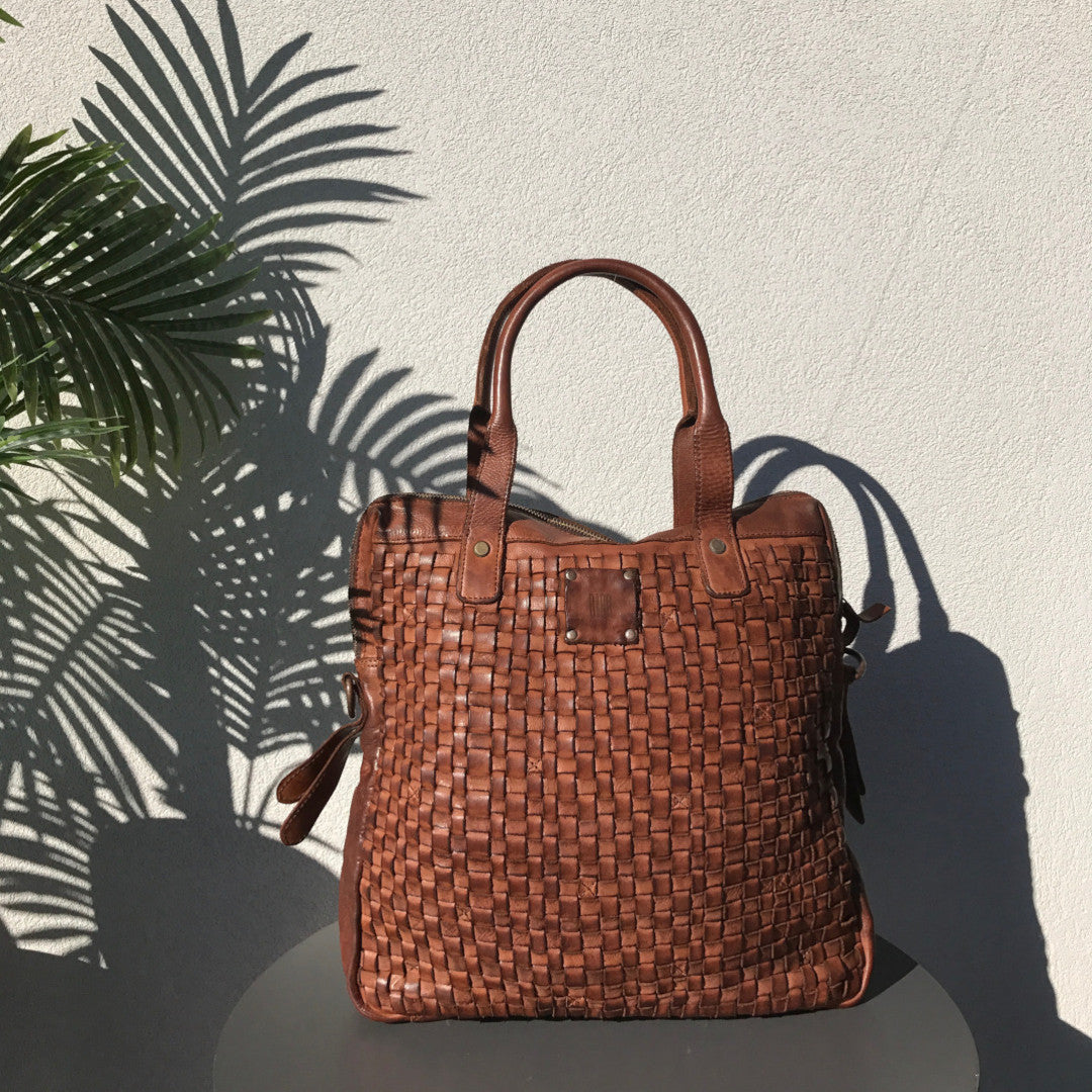 camel_hand_bag_by_BIBA_on_top_of_a_bench_in_front_of_a_white_wall