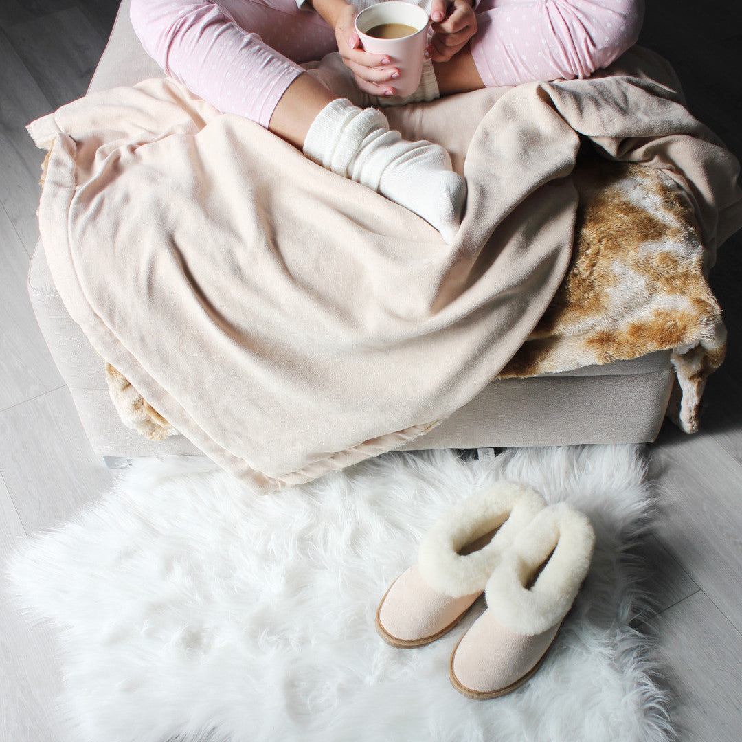 top_overview_person_on_couch_with_coffee_sheep_skin_slippers_on_floor